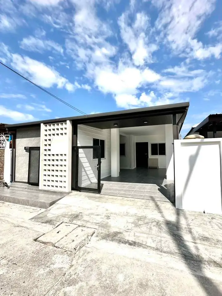 Modern single-story house with sleek design and spacious driveway under a clear blue sky.