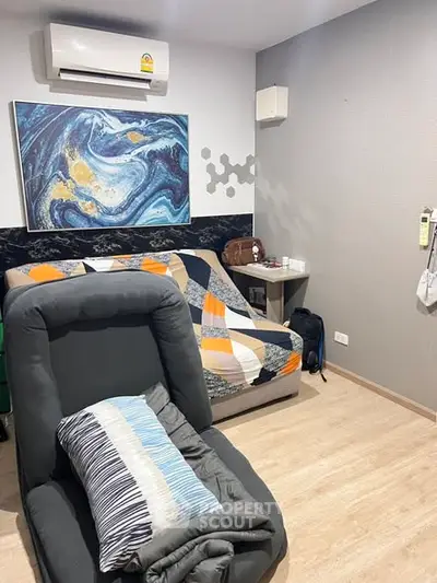Cozy bedroom with modern decor and air conditioning, featuring a comfortable chair and stylish artwork.