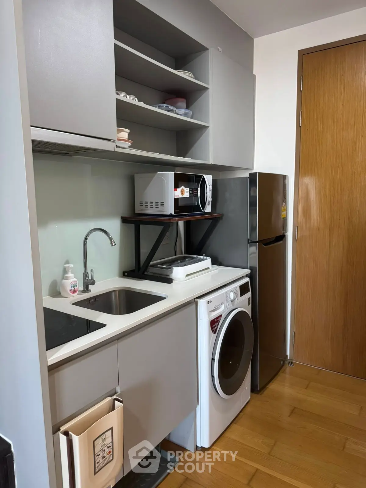 Compact kitchen with modern appliances, washing machine, and ample storage space.