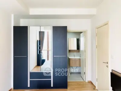 Modern bedroom with sleek wardrobe and ensuite bathroom in minimalist design.