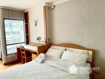 Cozy bedroom with natural light, featuring a comfortable bed and a functional study desk by the window.