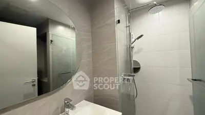 Modern bathroom with sleek shower and round mirror in contemporary apartment.