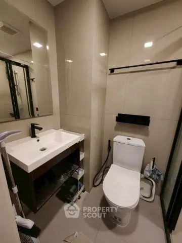 Modern bathroom with sleek fixtures and neutral tones, featuring a toilet and sink.