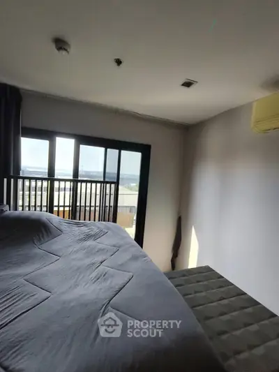 Spacious bedroom with large window offering stunning city views and modern decor.