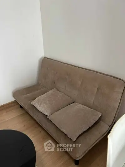Cozy living room corner with a beige sofa and wooden flooring