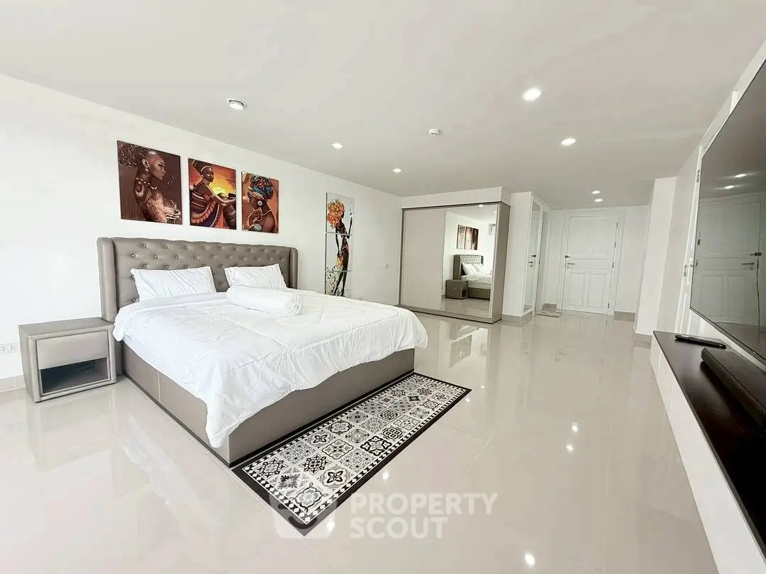 Spacious modern bedroom with elegant decor and large mirror