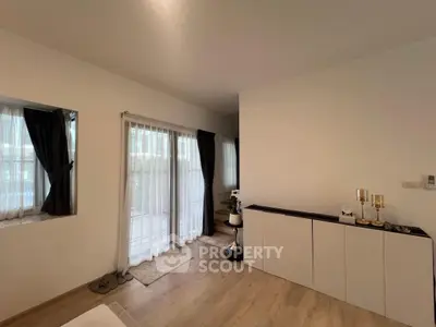 Elegant living room with large windows and modern decor, featuring a cozy ambiance and natural light.