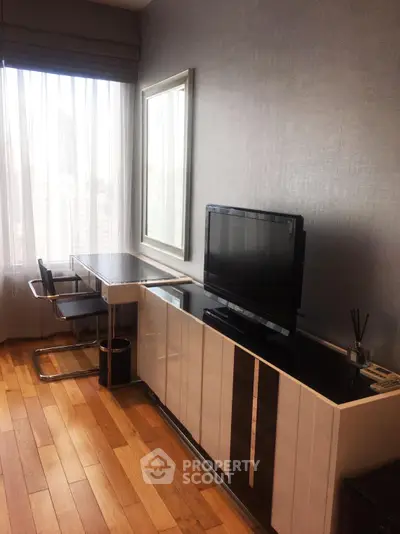 Modern living room with sleek furniture and large window offering city views.