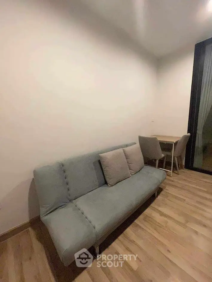 Cozy living room with modern sofa and dining table, perfect for small spaces.