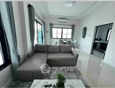 Modern living room with sleek gray sofa and large windows, offering a bright and inviting atmosphere.