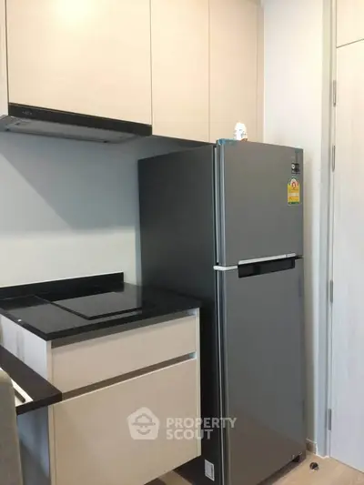 Modern kitchen with sleek cabinetry and stainless steel fridge in compact layout.