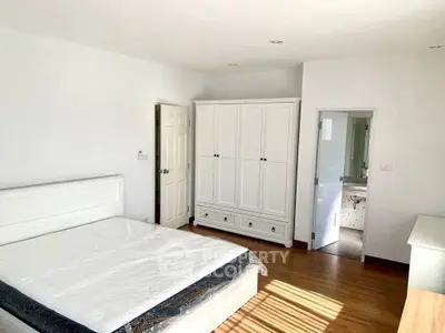 Bright and spacious bedroom with wooden flooring and modern white furniture