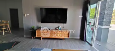 Modern living room with wall-mounted TV and stylish wooden cabinet, featuring open balcony access and natural light.