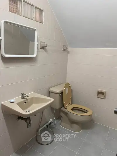 Compact bathroom with beige fixtures and wall-mounted mirror in a tiled setting.