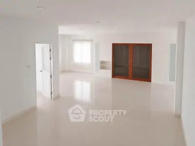 Spacious empty living room with glossy floors and large window, perfect for customization.