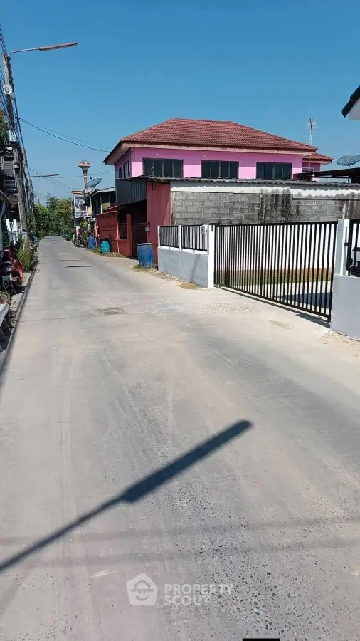 Charming suburban street with colorful houses and gated properties under clear blue sky.