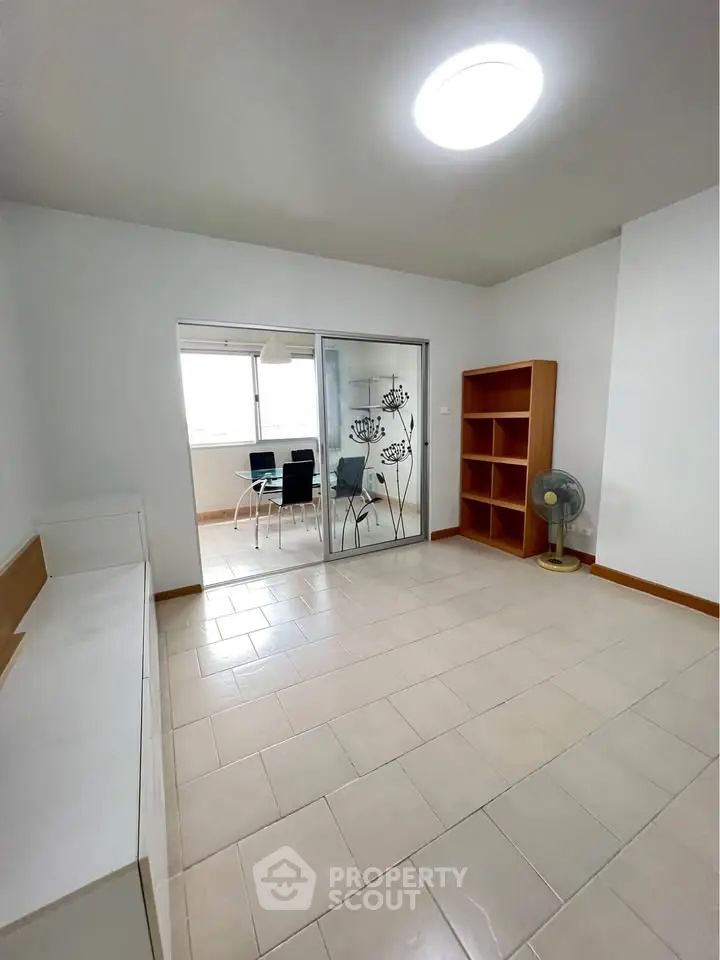 Spacious living room with sliding glass doors leading to a bright dining area, featuring modern decor and ample natural light.