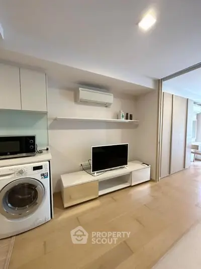 Modern living room with sleek TV unit, washing machine, and air conditioning in a stylish apartment.