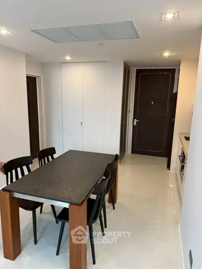 Modern dining area with sleek black table and chairs in a minimalist apartment interior.