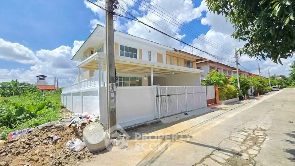 Modern two-story house with spacious balcony and gated entrance in a suburban neighborhood.