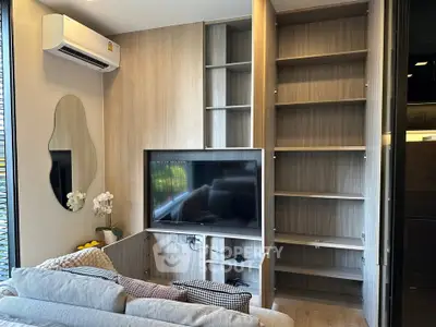Modern living room with built-in shelves and TV, featuring stylish decor and air conditioning.