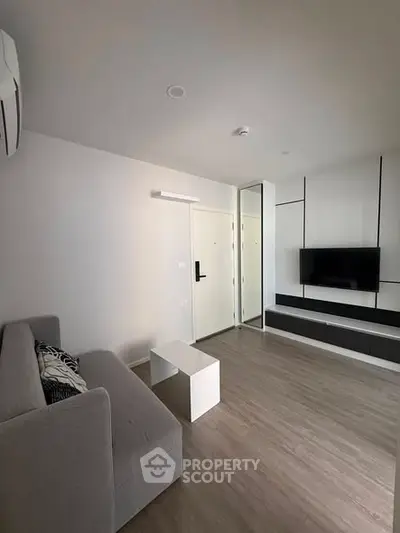 Modern living room with sleek design, featuring a wall-mounted TV and stylish furniture.