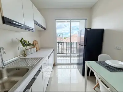 Modern kitchen with sleek cabinetry and balcony view, featuring a spacious fridge and dining area.
