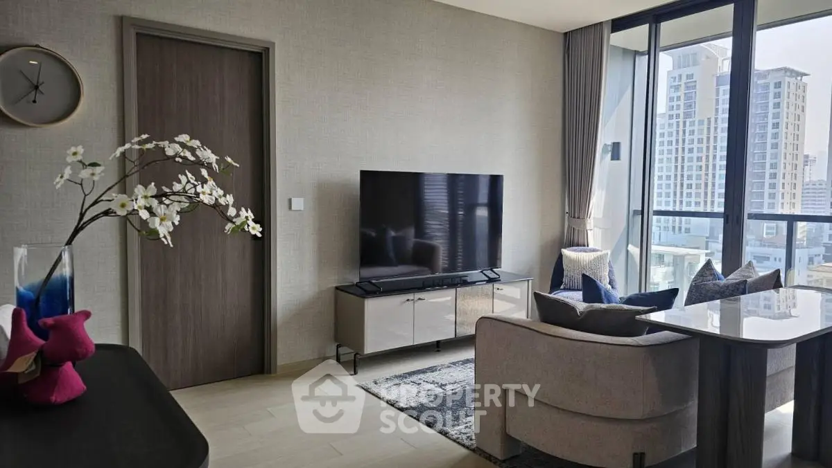 Modern living room with large TV and city view, featuring stylish decor and ample natural light.