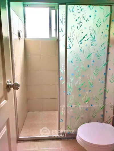 Bright bathroom with floral glass shower door and natural light