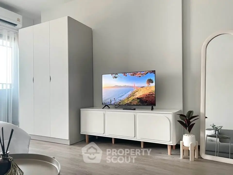 Modern living room with sleek white furniture and a flat-screen TV, perfect for stylish urban living.