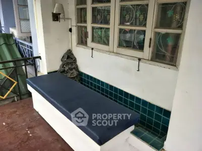 Charming balcony with tiled seating area and vintage windows, perfect for relaxation.