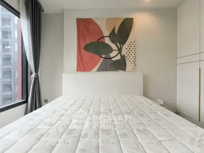 Modern bedroom with stylish decor and large window offering city views.