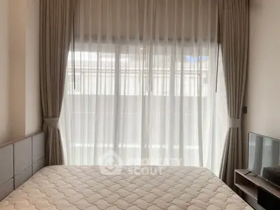 Cozy bedroom with large window and elegant curtains, featuring a comfortable bed and modern TV setup.