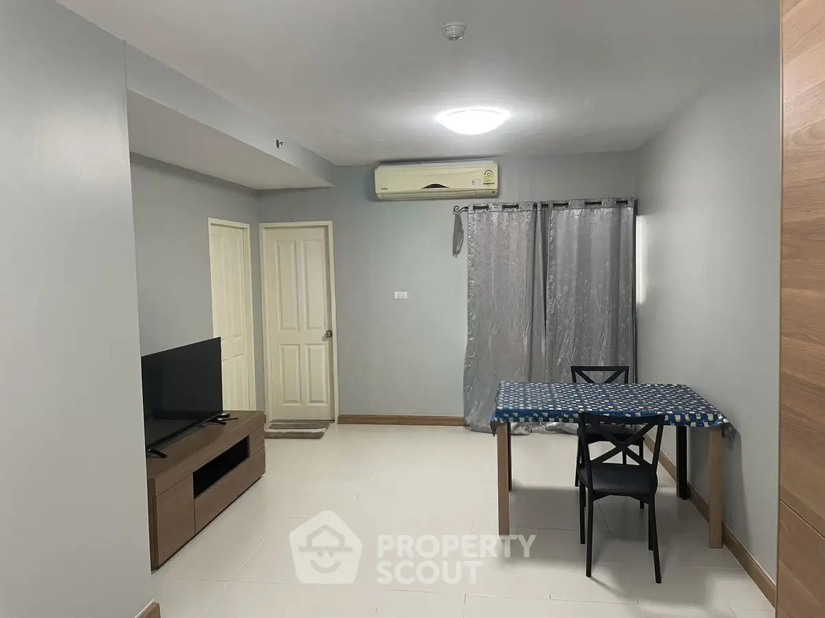 Modern living room with minimalist decor, featuring a TV and dining area in a cozy apartment.