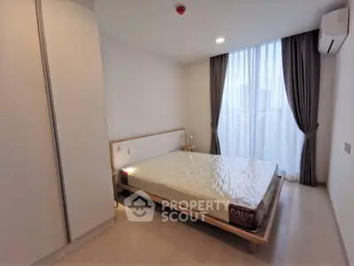 Spacious and well-lit bedroom with modern design, featuring a large bed, elegant curtains, and a sleek air conditioning unit.