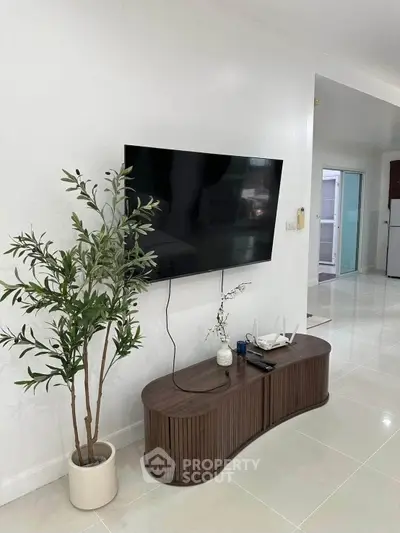 Modern living room with wall-mounted TV and stylish wooden console in a bright, minimalist interior.