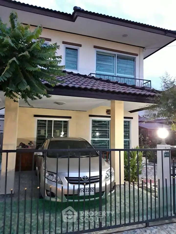 Charming two-story house with carport and lush greenery, perfect for family living.