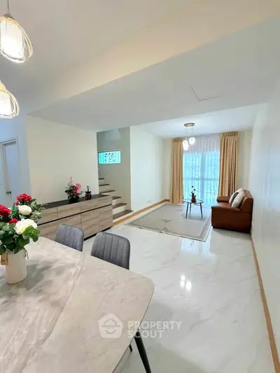 Spacious living room with elegant decor and natural light, featuring a cozy seating area and modern dining space.