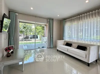 Spacious living room with elegant decor and garden view, featuring large windows and modern furniture.