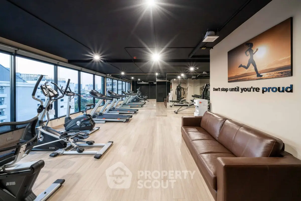 Modern gym with cardio equipment and motivational decor in a sleek apartment building.