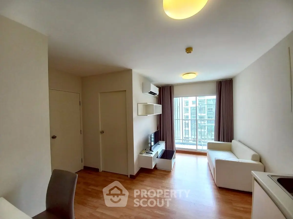 Modern living room with wooden flooring and balcony view in a stylish apartment.