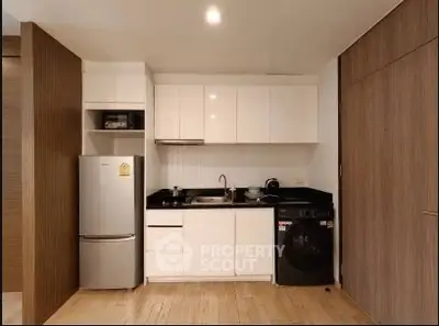 Modern compact kitchen with sleek white cabinets and integrated appliances in a stylish apartment.