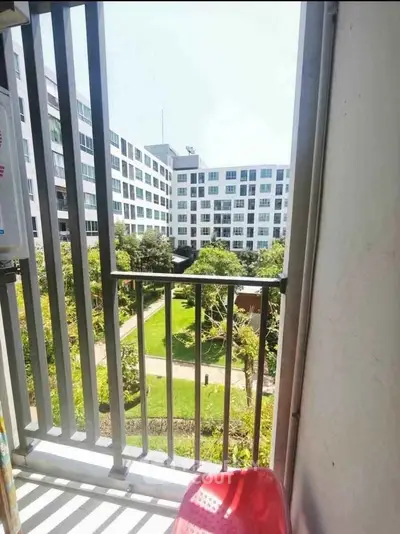 Charming balcony view overlooking lush garden in modern apartment complex.