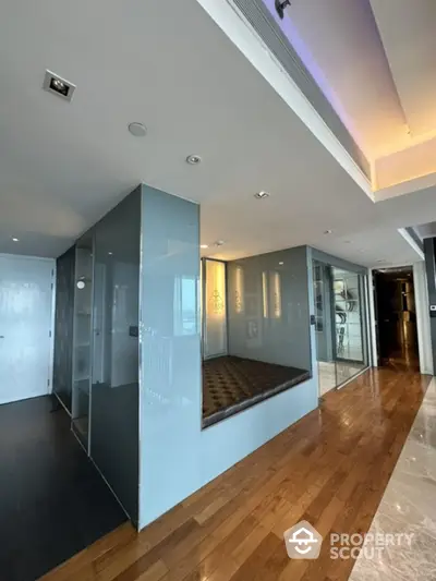 Modern hallway with sleek glass walls and wooden flooring in luxury apartment