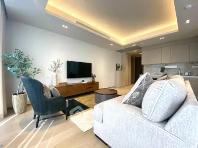 Modern living room with stylish furniture and open kitchen layout, featuring elegant lighting and decor.