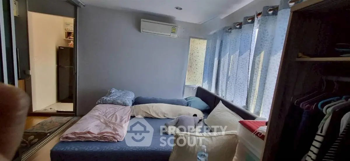 Cozy bedroom with natural light, featuring a comfortable bed and modern air conditioning.