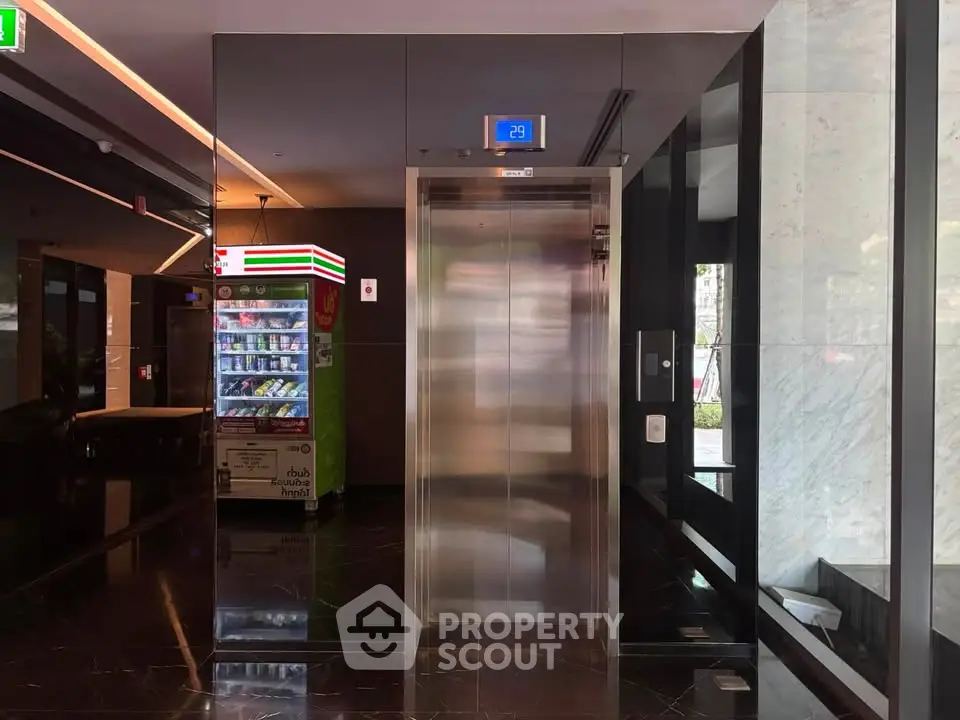 Modern building lobby with elevator and vending machine, sleek design and polished floors.