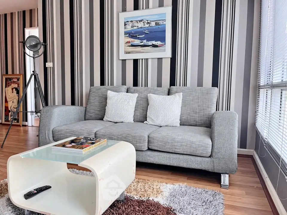 Stylish modern living room with grey sofa, striped wallpaper, and chic decor accents.
