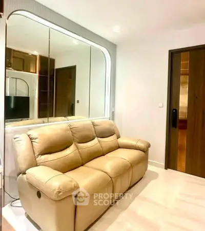 Modern living room with beige leather sofa and mirrored wall for spacious feel.