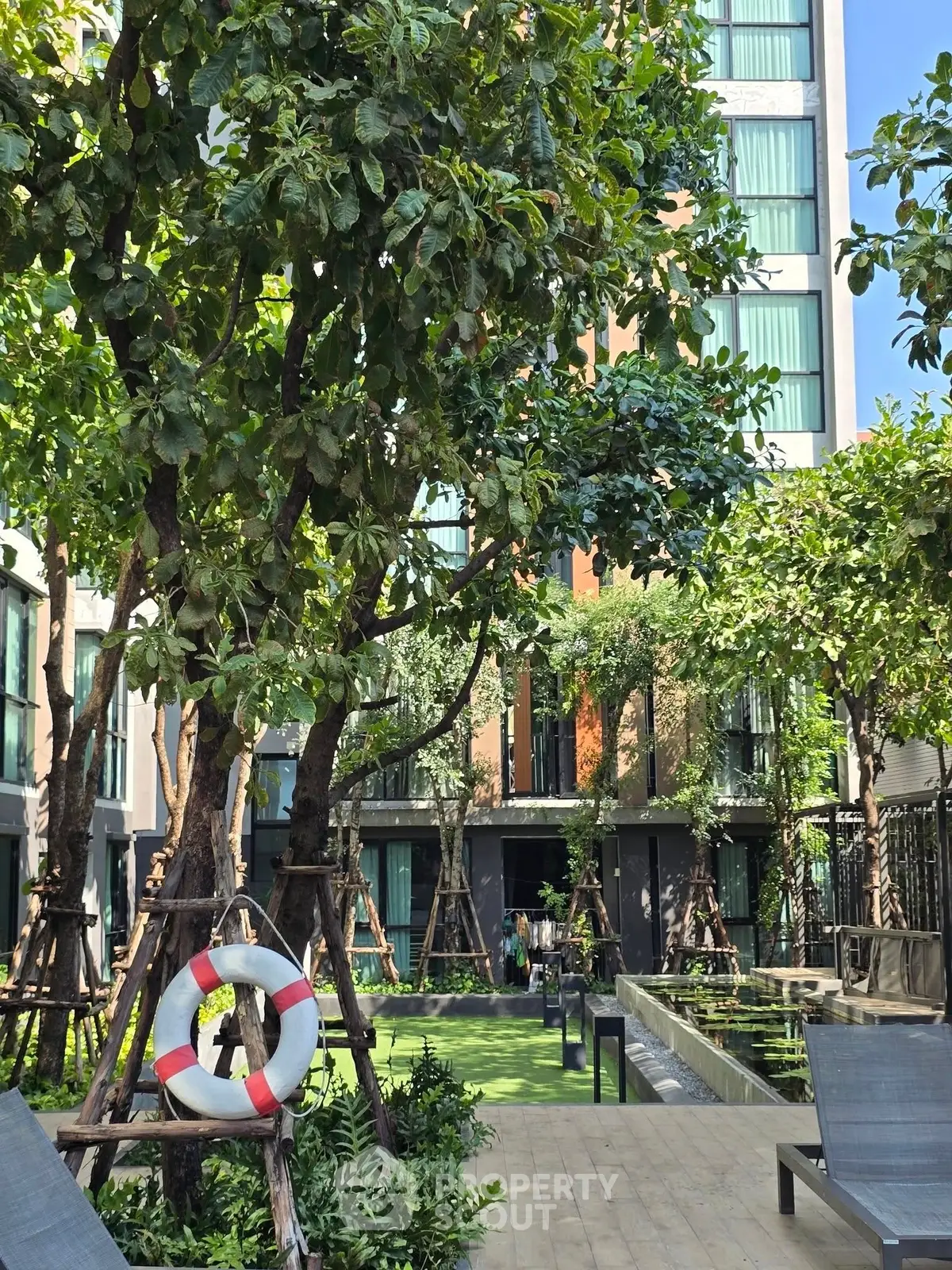 Luxurious garden area with lush greenery and modern apartment building backdrop.